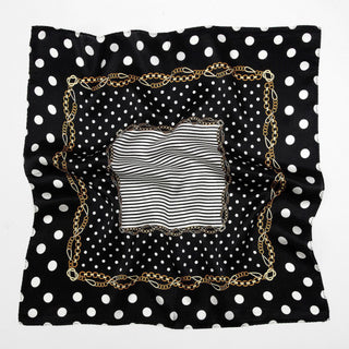 Square silk scarf with black and white polka dot pattern, gold chain border, and central striped design, displayed flat showing luxurious sheen