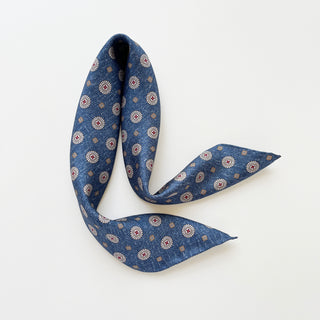 Denim blue silk neckerchief with taupe medallion pattern, elegantly folded to display its 53cm hand-rolled edges and classic design