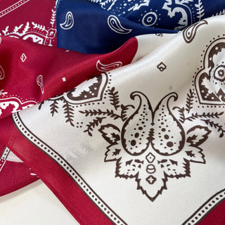 Three luxurious silk bandanas with paisley patterns in plum red, navy blue, and cream white colors, showcasing intricate boho designs.