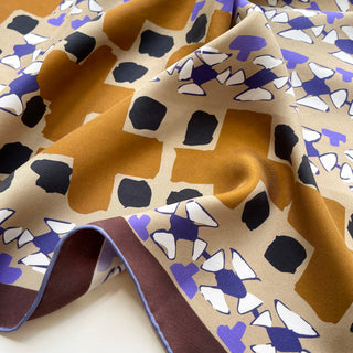 Close-up of 65cm unisex silk scarf with abstract geo print in mustard, black, beige, purple and brown, on matte silk twill
