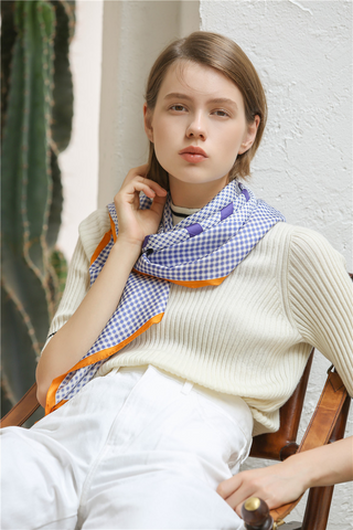 Women’s silk scarf 90cm in blue checks and houndstooth with orange border, hand-rolled edges, styled around the neck.
