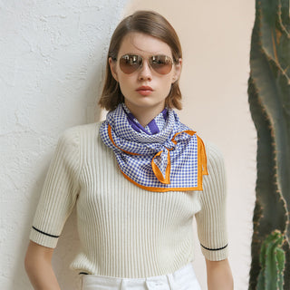 Women’s silk scarf 90cm in blue checks and houndstooth with orange border, hand-rolled edges, styled around the neck.