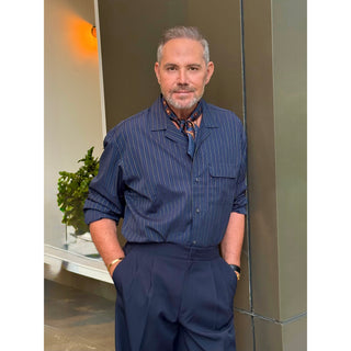 Man wearing a navy paisley silk square scarf by LuluLane in striped navy shirt and navy trousers showcasing a sharp and refined look.