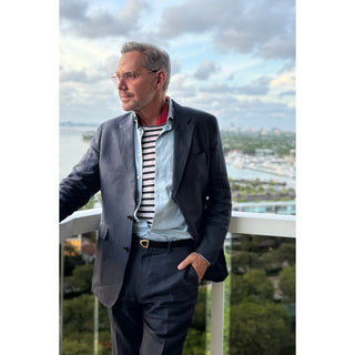 Man wearing a red paisley silk neckerchief with a navy linen blazer and striped Breton shirt, styled for a smart casual summer look.