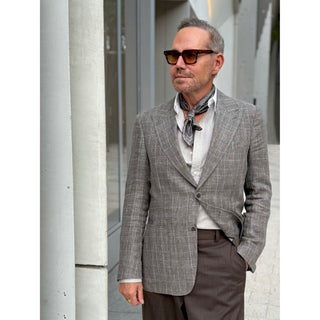 Man wearing a grey and taupe tone patterned silk square from LuluLane in a grey suit and sunglasses showcasing a polished smart casual look.