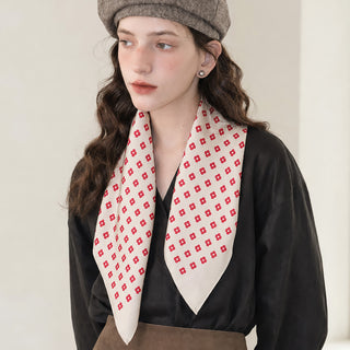 Woman wearing an ivory and red mini floral silk square scarf loosely around her neck, styled with a black blouse, brown skirt and tweed beret.
