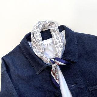 White silk neckerchief with navy medallion pattern styled with denim jacket and white shirt, showcasing elegant men's accessory styling.