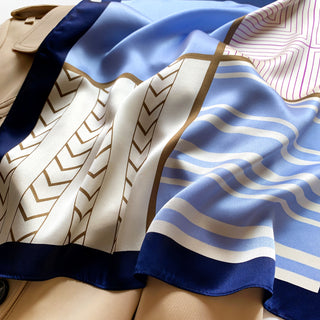 Luxurious silk bandana featuring modern geometric patterns with blue, white, and gold colors, showing chevron and stripe designs with a navy border