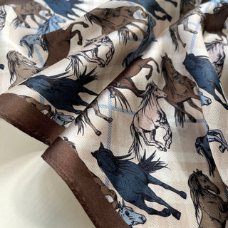 Luxurious silk bandana with elegant wild horse pattern in navy, brown and cream tones, featuring galloping horses with flowing manes and brown border trim