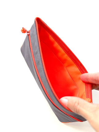 Recycled double zipper wallet open to show bright neon orange interior with card slots and gray exterior, featuring orange piping detail