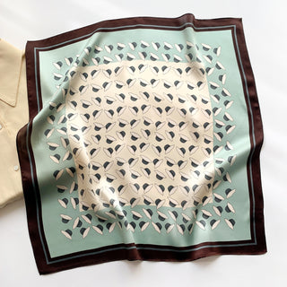 Square silk bandana featuring dancing hat pattern with mint green background, cream center, and brown border, displayed flat showing elegant design