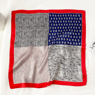 Square silk neckerchief with patchwork design featuring navy paisley, gray pattern, light pink paisley, and textured white quadrants with bright red border