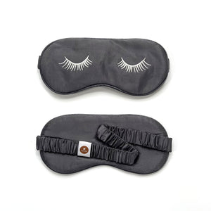 a grey silk eye mask featuring eyelashes embroidery and elastic strap with a logo lululane