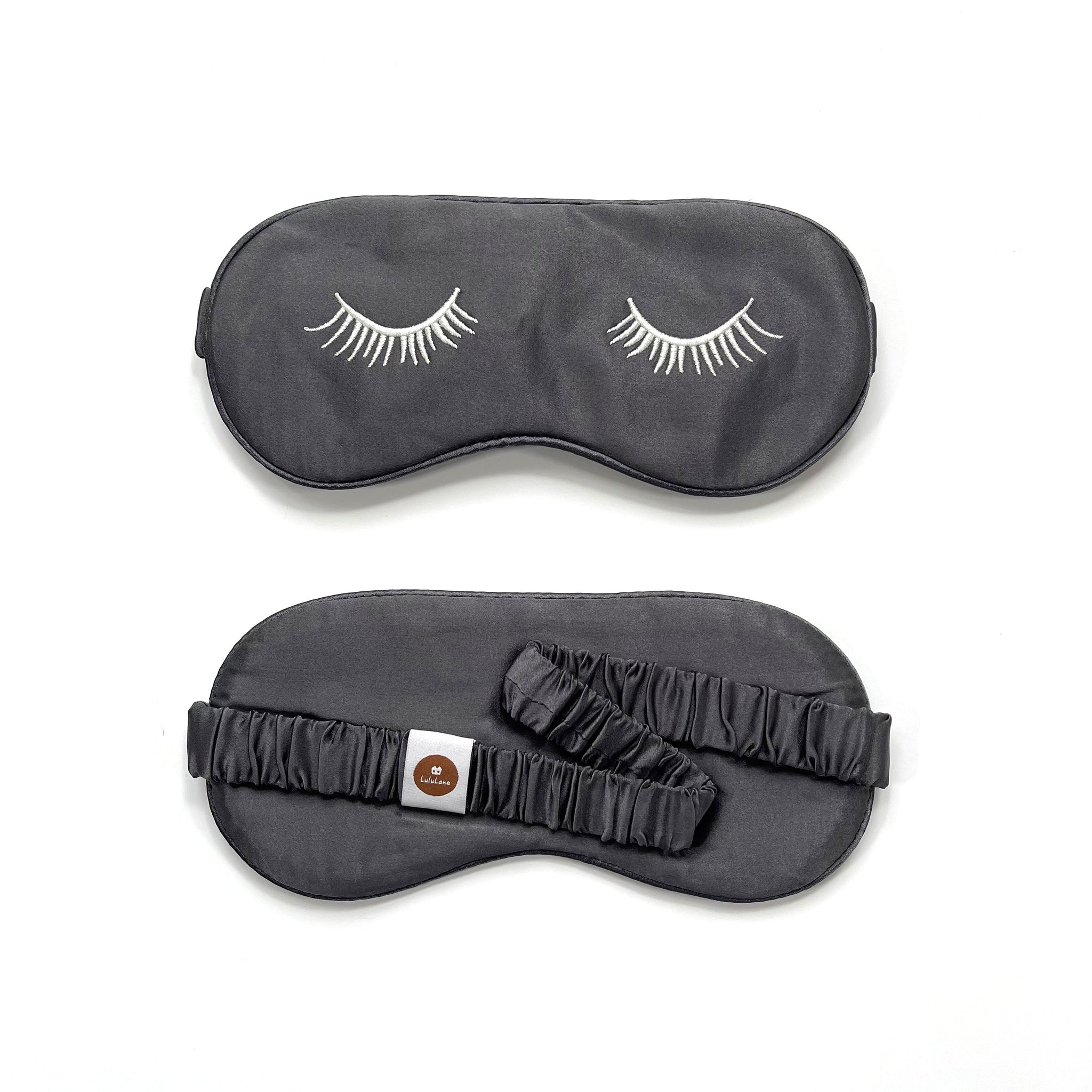 a grey silk eye mask featuring white eyelashes embroidery and elastic strap