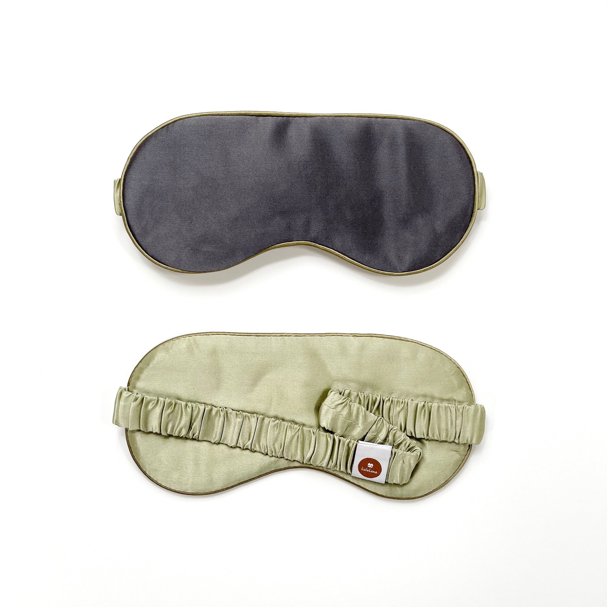 a professionally designed and handcrafted dark grey silk eye mask featuring a pea green back side, a pea green drawstring and a pea green elastic strap