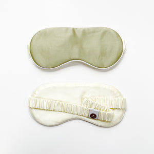 a professionally designed and handmade pea green silk eye mask with creamy white elastic strap and back side 
