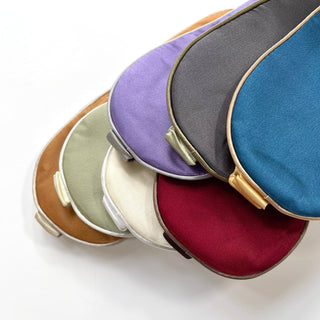 Luxurious silk sleep masks in multiple colors including rich blue, purple, gray, cream, mint, burgundy and copper, each with elegant piping and adjustable straps.